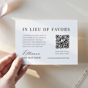 May include: A white card with black text that reads "In Lieu of Favors". The text explains that a donation has been made to the American Cancer Society in honor of the couple's wedding. A black and white QR code is included with the text "Scan here to see their great work" and the website "lilliannaandmatthew.com".
