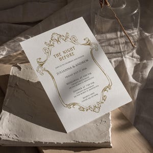May include: A white invitation with gold lettering announcing "The Night Before" for Julianna & Andrew. The event will take place on Friday, July 17, 2026, with a rehearsal at 5:00 PM and dinner at 7:00 PM at Chianti Restaurant, 201 Van Buren St. Montecito. The invitation includes contact information for regrets only.