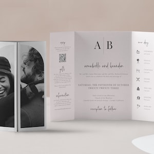 May include: A wedding invitation with a black and white photo of a couple on the front. The invitation is folded in thirds and includes the couple's names, the date and time of the wedding, and the location. The back of the invitation lists the order of events for the wedding day.