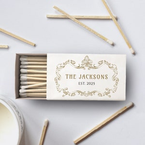 Peut inclure: Une boîte d'allumettes blanche avec un motif doré et le texte "THE JACKSONS EST. 2025".