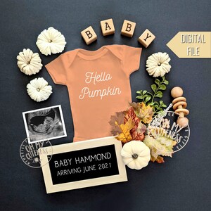 Puede incluir: Un archivo digital para un anuncio de nacimiento con un body de color melocotón con el texto "Hello Pumpkin" en él. El body está rodeado de decoraciones de otoño, incluyendo calabazas, hojas y un sonajero de madera para bebé. Un letrero de pizarra negra dice "Baby Hammond Arriving June 2021".