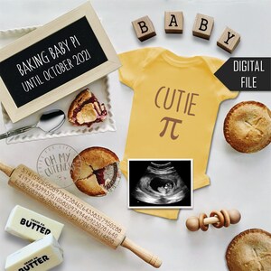 May include: A baby announcement featuring a yellow onesie with "Cutie π" printed on it, surrounded by pie, a rolling pin with numbers, ultrasound image, and wooden blocks spelling "BABY". A chalkboard reads "Baking Baby Pi Until October 2021".
