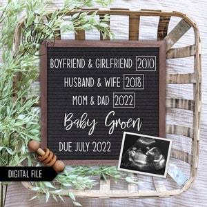 May include: A black letter board with white text announcing the arrival of "Baby Groen" due in July 2022. The board also lists the years the couple became boyfriend and girlfriend, husband and wife, and mum and dad. A black and white ultrasound image is displayed next to the board.
