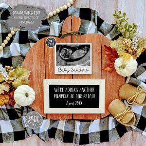 以下が含まれることがあります： 「We're adding another pumpkin to our patch! April 202X」と書かれた黒いチョークボードのインサートが付いた木製のカボチャ型のサイン。チョークボードの上に、「Baby Sanders」と書かれた超音波画像が額装されています。サインの周りに、白いカボチャ、秋の葉、ベビーシューズが配置されています。