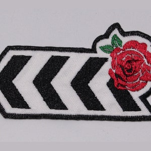 May include: Black and white chevron patch with a red rose embroidered on the right side. The rose has green leaves.