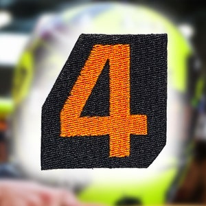 Puede incluir: Un parche de tela negro con un número "4" bordado en naranja.