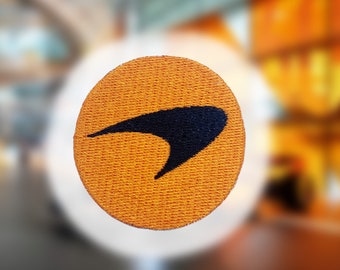 May include: A round orange fabric patch with a black stylized spaceship design.