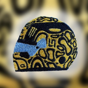 May include: Embroidered patch with a unique design. The patch features a combination of black, gold, and blue colors. The design includes abstract shapes and patterns, creating a textured appearance. The patch is likely for clothing or accessories.