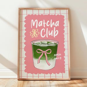 May include: A framed print featuring a matcha drink illustration. The artwork has a pink background with the words "Matcha Club" and "Open Daily." The matcha drink is green with ice cubes and a pink bow.