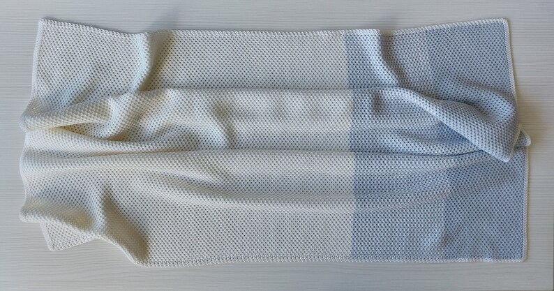 May include: A white and light blue waffle knit throw blanket with a textured pattern. The blanket is folded in half and has a soft, cozy look.