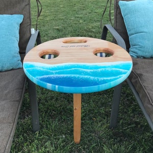 handmade sanded and stained folding portable outdoor table with 2 drink holders fitting drinks of various sizes. Available in light, medium, dark, vintage aqua stain color or light stain will add-on epoxy beach art resembling waves on the sand beach