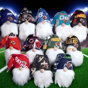 May include: A collection of gnome figurines, each with a white beard and a hat featuring the logos of various American football teams. The hats display team names and colors, set against a green field background.