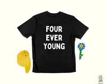 May include: Black t-shirt with the text "FOUR EVER YOUNG" printed in white on the back. A yellow baseball cap and a blue and green flower made of candy are also in the image.