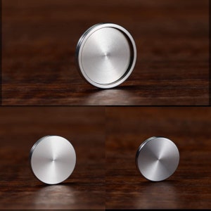 May include: Three silver metal discs of varying sizes. The discs are smooth and have a shiny finish.