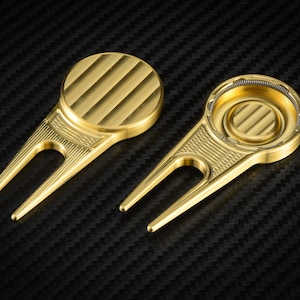 May include: Two gold golf ball retrievers with a textured design. One retriever has a round top and the other has a round top with a small, circular, indented area.