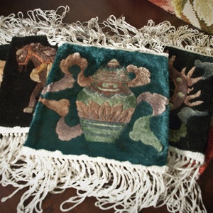 May include: Four embroidered wall hangings with fringe. The hangings feature a green background with a vase of flowers, a black background with a horse, a black background with a floral design, and a red background with a floral design.