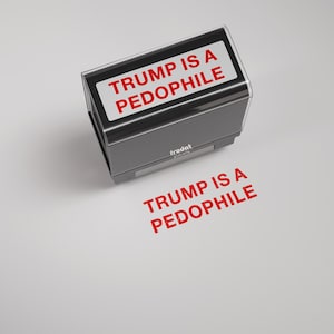 May include: A black and silver stamp with the text "TRUMP IS A PEDOPHILE" in red. The stamp has a rectangular design and is positioned above a stamped impression of the same text.