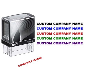 May include: A clear and black COLOP Printer 20 stamp with the text "CUSTOM COMPANY NAME" in various colors. The stamp also has the text "COMPANY NAME" in red.