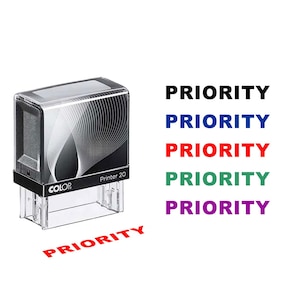 Peut inclure: Un tampon encreur noir et transparent avec le mot "PRIORITY" imprimé en rouge. Le tampon a un design noir et argenté sur le dessus et le texte "COLOR Printer 20". Le mot "PRIORITY" est également imprimé en noir, bleu, rouge, vert et violet.