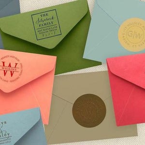 K&ouml;nnte beinhalten: Eine Sammlung von Umschl&auml;gen mit verschiedenen personalisierten Briefmarken. Die Briefmarken zeigen verschiedene Designs, darunter Initialen, Familiennamen und dekorative Muster. Die Umschl&auml;ge sind in verschiedenen Farben, darunter rosa, gr&uuml;n, blau und rot.
