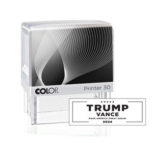 May include: A white and black self-inking stamp with the text "COLOP Printer 30" on the front. The stamp is designed to print the text "TRUMP VANCE MAKE AMERICA GREAT AGAIN! 2024" in black ink.