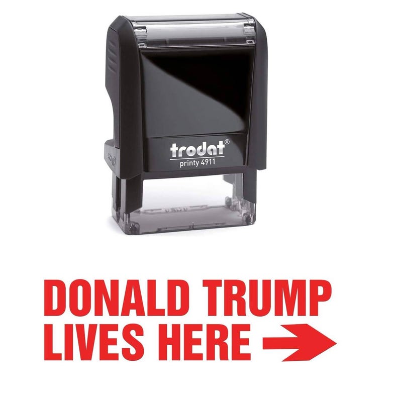Peut inclure: Un tampon encreur noir avec le texte "trodat printy 4911" sur le devant. Le tampon est con&ccedil;u pour cr&eacute;er une empreinte rouge avec le texte "DONALD TRUMP LIVES HERE" et une fl&egrave;che rouge pointant vers la droite.
