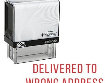 Könnte beinhalten: Ein roter Stempel aus Gummi mit dem Text "DELIVERED TO WRONG ADDRESS" in weißen Buchstaben. Der Stempel wird von 2000 PLUS hergestellt und trägt das Microban-Logo.