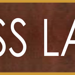 Peut inclure: Une plaque en métal brun rouillé avec le texte "BOSS LADY" en lettres blanches.