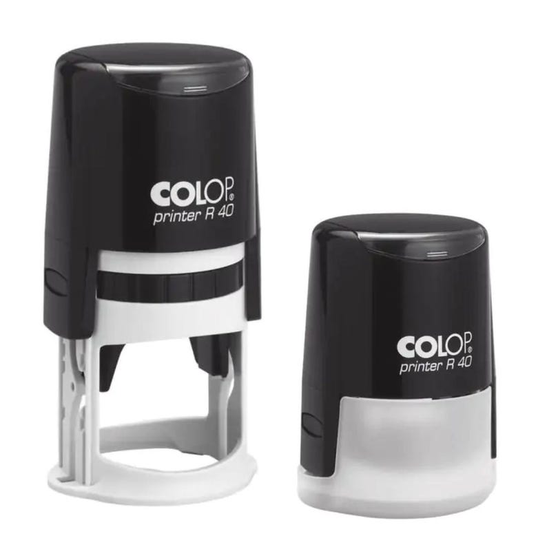 K&ouml;nnte beinhalten: Zwei schwarze selbsttinten-Stempel mit wei&szlig;em Text, der "COLOP printer R 40" lautet. Die Stempel sind unterschiedlich gro&szlig; und haben eine wei&szlig;e Kunststoffbasis.