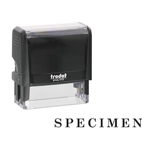 May include: A black self-inking stamp with a clear base, featuring the brand name Trodat and model number printy 4915 printed on the front. Below the stamp, the word SPECIMEN is displayed in a bold, black, serif font on a white background.