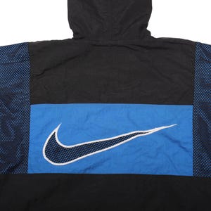 May include: Black and blue Nike windbreaker jacket with a hood. The jacket features a large white Nike swoosh logo on a blue stripe across the chest. The sides have a blue mesh design.