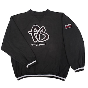 May include: A black long-sleeve sweatshirt featuring a large white outlined 'fb' logo on the chest with the text 'Fubu' underneath. A small rectangular patch on the left sleeve displays 'FUBU' and 'SINCE 1992'. The cuffs and hem have white and black stripes.