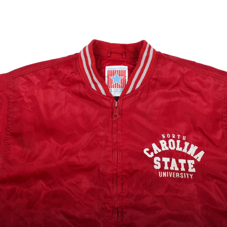 campus apparel, thrifted stadium outfit , crimson red fabric, scarlet nylon shell, arched white spellout, striped ribbing cuffs, grey stripe collar, elastic waist hem, full zip closure, track jacket design, side slash pockets, true vintage character, natural soft sheen, thrifted designer look, vintage casuals shop, classic retro colorway, midwest sports history, comfortable winter jacket, everyday layer coat, grandpacore basic style, unisex streetwear drip