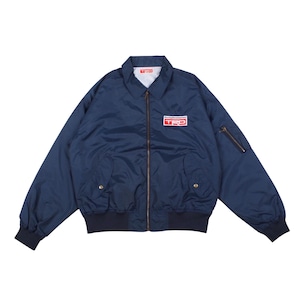 Peut inclure: Un blouson bleu marine avec une fermeture éclair frontale, un col pointu, ainsi que des poignets et un ourlet côtelés. Un écusson rectangulaire sur la poitrine gauche affiche le texte Racing Development TRD en blanc et rouge. Une poche zippée est présente sur la manche.