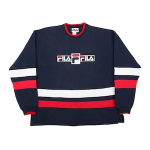 vintage 90s navy blue Fila crewneck sweatshirt on a white background, featuring a bold white and red embroidered Fila logo in the center chest and matching solid horizontal white and red stripes across the lower body and sleeves with a red ringer collar