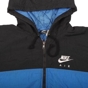May include: Black, blue, and white Nike Air hooded jacket. The jacket has a black hood and upper body, a blue lower body, and a blue quilted lining. The Nike logo and "AIR" are printed in white on the chest. The jacket has a full zipper.