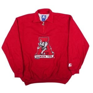 May include: A red long-sleeve pullover sweatshirt with a quarter-zip collar. The front features a large graphic of an elephant inside a letter A with the text Crimson Tide. A Starter logo is embroidered on the left sleeve and the inner neck label.