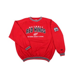 May include: Red Detroit Red Wings sweatshirt. The red sweatshirt features the team name and logo in white and black, with the words "National Hockey League" below. The sleeves and collar have black and white stripes.