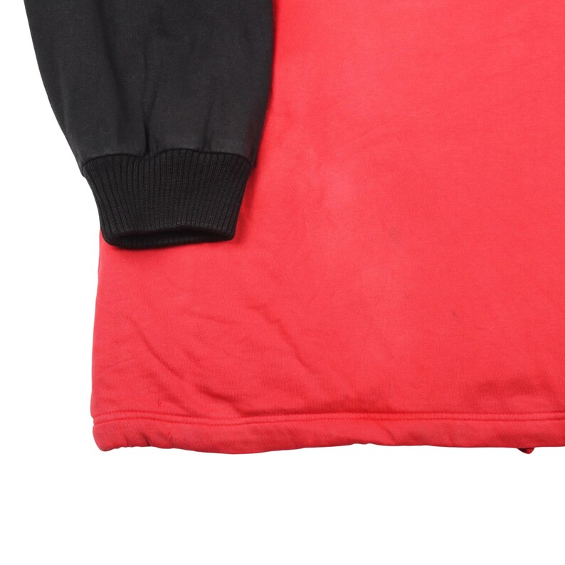 Pu&ograve; includere: Una maglietta rossa a maniche lunghe con una manica nera. La manica nera ha un polsino a coste. La maglietta &egrave; realizzata in un materiale morbido.