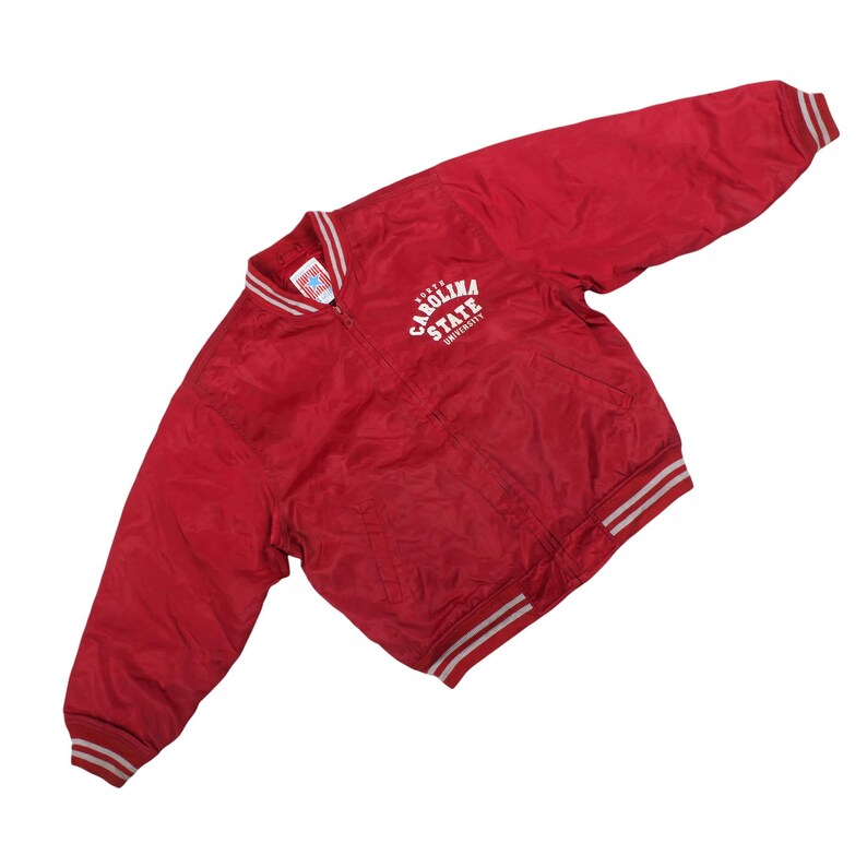 vintage NC State varsity jacket, 90s North Carolina State windbreaker, crimson red retro college bomber coat, arched white university spellout top, striped ribbing collar sports sweater, classic nineties collegiate fan apparel, lightweight red nylon track jacket, old school loose fit ivy league clothing, vintage midwest carolina sports merch, thrifted nineties skate streetwear outerwear, cozy autumn weather resistant wind shell, unisex oversized boxy fit coach jacket,