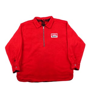 May include: A bright red fleece pullover with a collared neckline and a quarter-zip closure. The shirt features long sleeves with buttoned cuffs and a small rectangular patch with the word "Marlboro". The interior collar has a black and red plaid pattern.