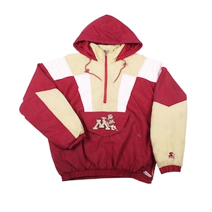 May include: Maroon, tan, and white hooded pullover jacket. The jacket features a half-zip closure, a kangaroo pocket, and the Minnesota Golden Gophers logo. The Starter logo is visible on the sleeve. A vintage athletic apparel item.