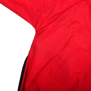 May include: A bright red garment featuring a smooth, lightweight fabric texture with a visible black panel along the side seam. The material appears to be a synthetic nylon or polyester blend with a slight sheen, showing a clean, solid color.