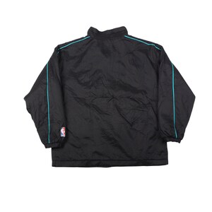 May include: Black nylon jacket with a high collar and turquoise trim along the shoulders and sleeves. Includes an NBA logo patch on the left sleeve. A lightweight, casual outerwear garment.
