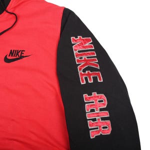 Pu&ograve; includere: Felpa con cappuccio Nike rossa e nera. La felpa ha un corpo rosso e maniche nere. Il logo Nike &egrave; ricamato in nero sul petto. La manica destra presenta la scritta "NIKE AIR" ricamata in rosso.
