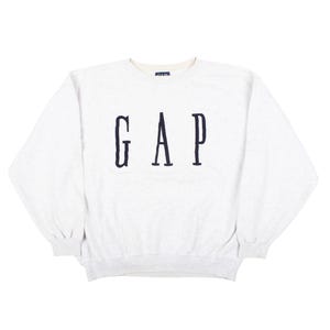 Könnte beinhalten: Ein hellgrau meliertes Sweatshirt mit Rundhalsausschnitt und dem Wort GAP in dunkelblauen Großbuchstaben auf der Brust. Das Kleidungsstück hat lange Ärmel mit gerippten Bündchen und einen gerippten Saum sowie ein kleines Markenetikett am Innenkragen.
