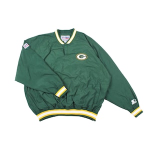 May include: Green and white pullover jacket with the Green Bay Packers logo. The jacket has a white collar and cuffs with yellow and green stripes. The Starter logo is visible on the sleeve.