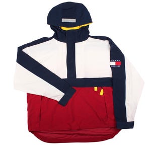 May include: A color-blocked pullover jacket featuring a navy blue hood with a yellow lining, a white upper chest, and a red lower section. The jacket includes a navy blue placket, long sleeves with navy blue stripes, and a Tommy Hilfiger logo patch.