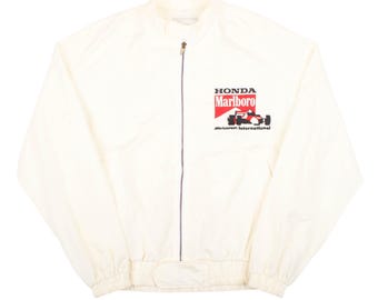 May include: A cream-colored zip-up jacket featuring a high collar and long sleeves. The front displays a graphic with the text Honda, Marlboro, and McLaren International, accompanied by an illustration of a Formula One race car in red, black, and white.