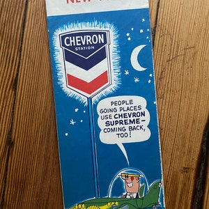 Könnte beinhalten: Eine Vintage-Straßenkarte der Chevron-Tankstelle für New York City. Die Karte zeigt eine Comic-Illustration eines Autos, das nachts mit einem Halbmond am Himmel fährt. Der Text lautet "Menschen, die Orte besuchen, verwenden Chevron Supreme - und kommen auch wieder!"